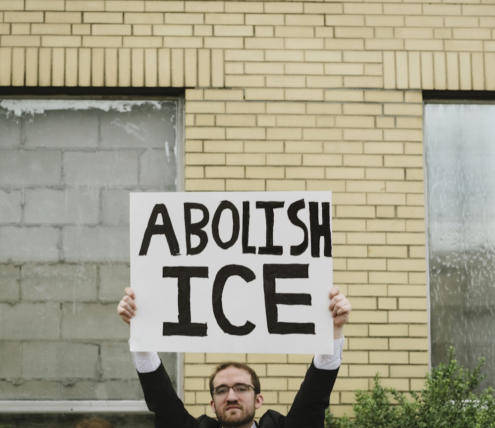 man holding banner with abolish ice print