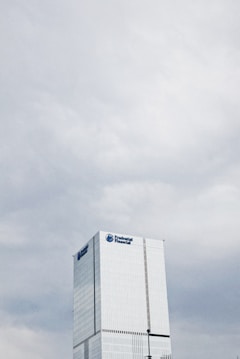A tall, modern skyscraper with a sleek glass facade and the Prudential Financial logo near the top, set against a backdrop of overcast skies.