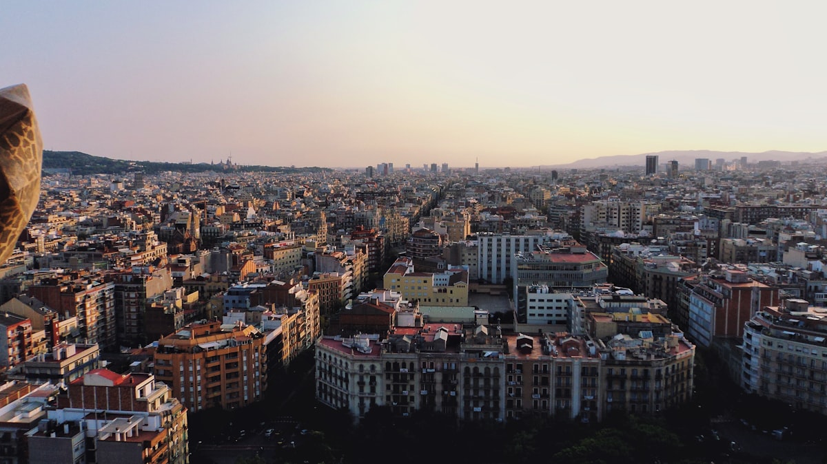 Aerial view of Barcelona's dense rooftops stretching to the Mediterranean at golden hour