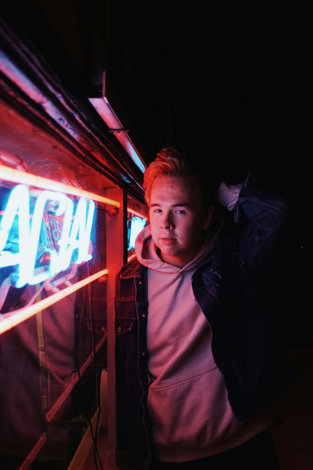 man standing beside neon light signage