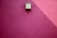 A smooth, pink plaster wall features a minimalist, rectangular light fixture casting a slanted shadow.