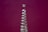 A tall, clear glass bottle with a spiral, ribbed design stands against a plain, deep magenta background. The bottle has a narrow neck and a round base.