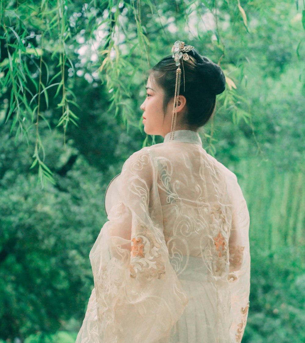 woman wearing white lace traditional trees looking at trees