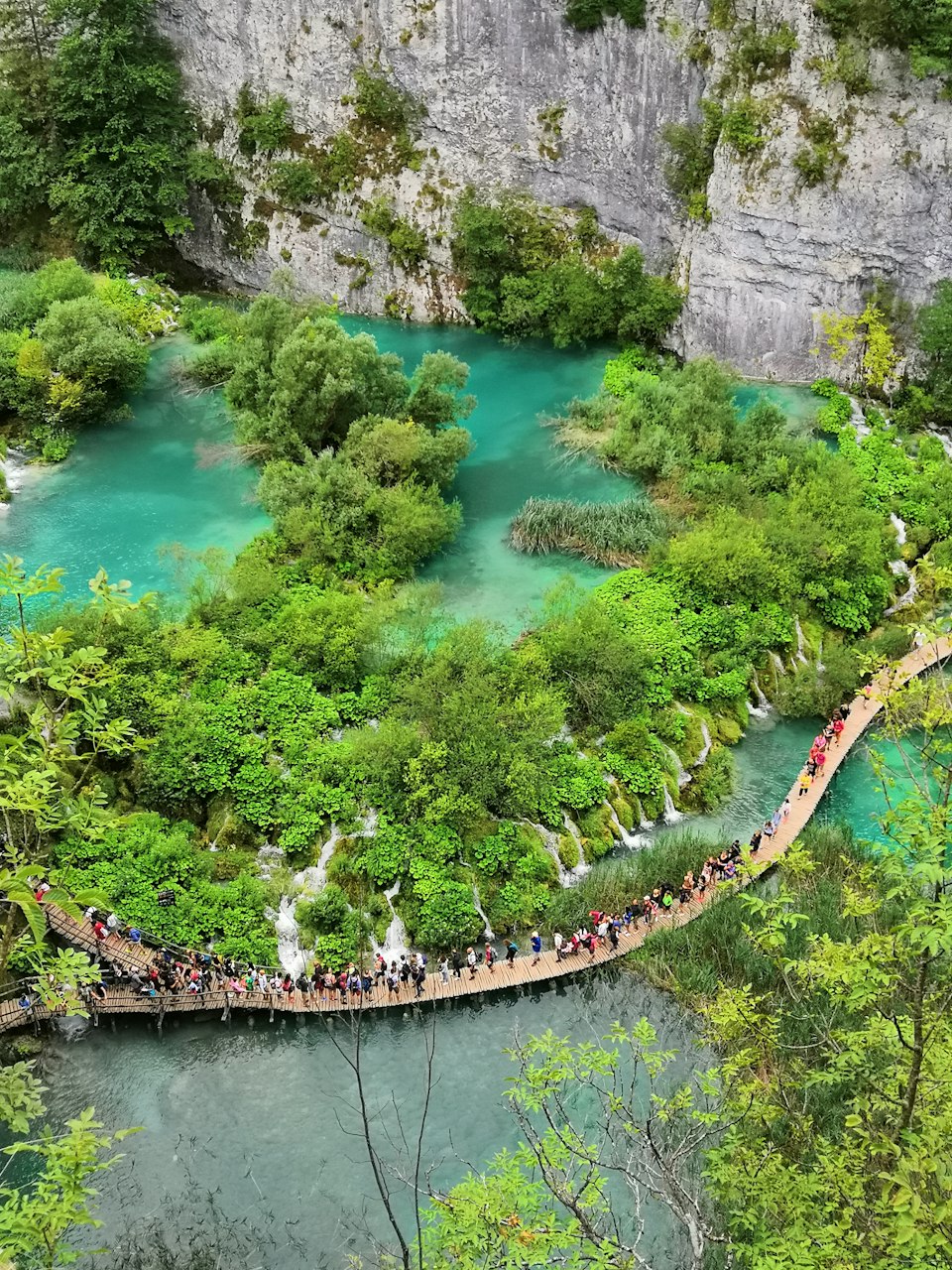 Aerial view of a turquoise pool and boardwalk trail through the terraced Upper Lakes at Plitvice