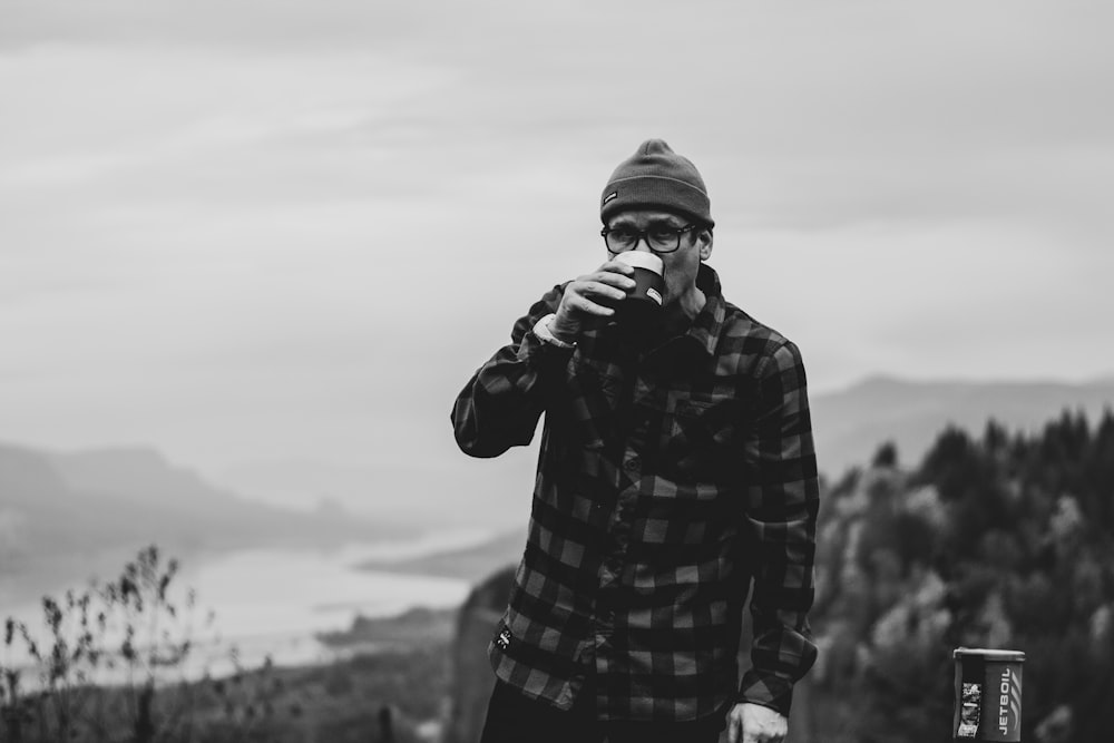 grayscale photo of man sipping on the mug