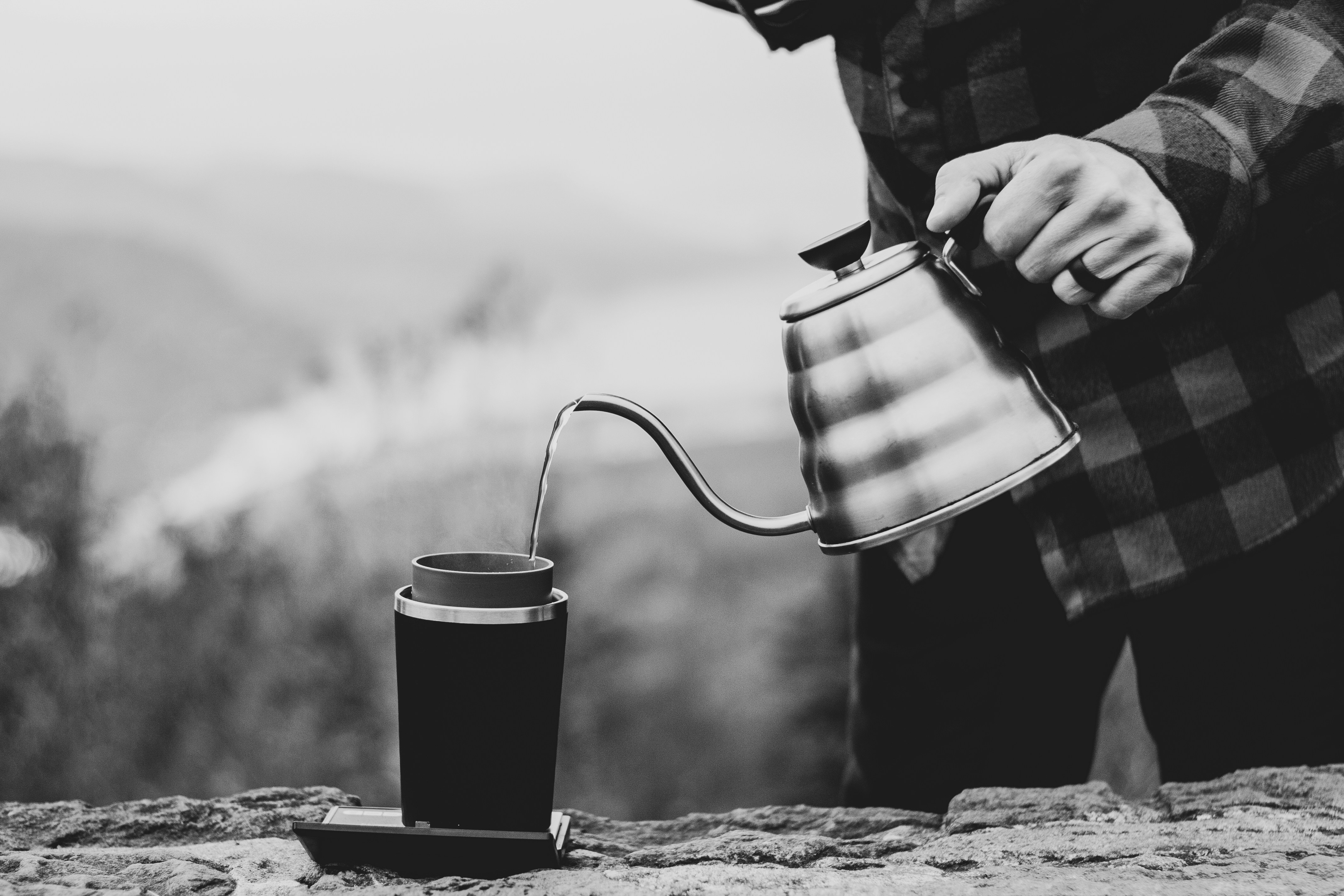 Black and white photo of a man pouring coffee outdoors