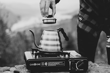 grayscale photo of person holding the lid of teapot