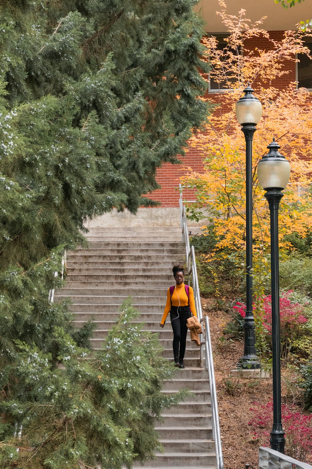 shallow focus photo of woman in orange long-sleeved shirt walking downstairs