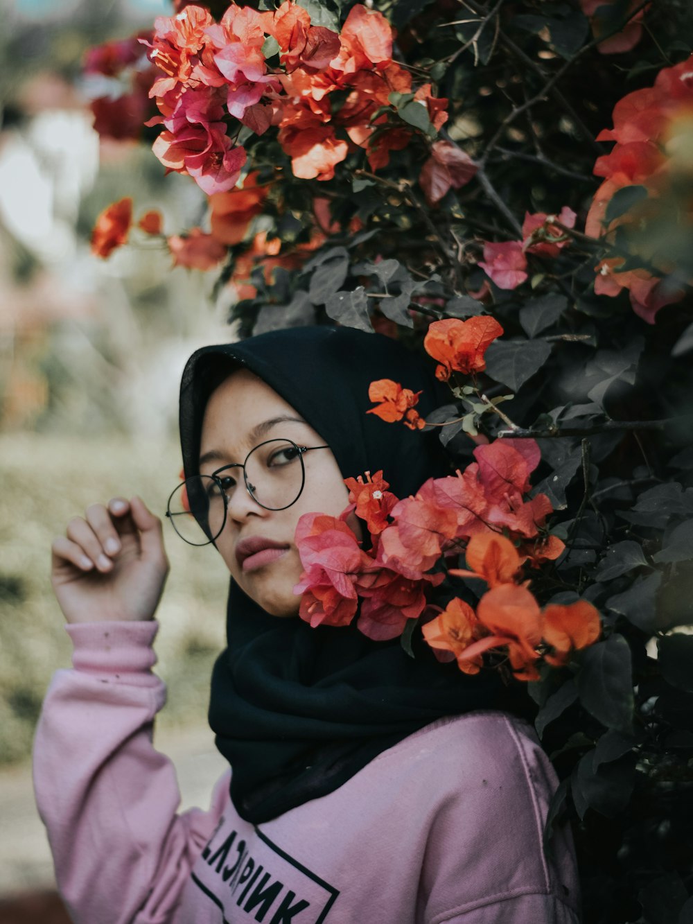 selective focus photography of woman standing beside flower during daytime