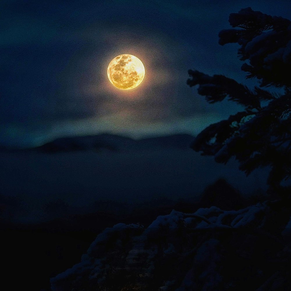 a full moon seen through the clouds in the night sky