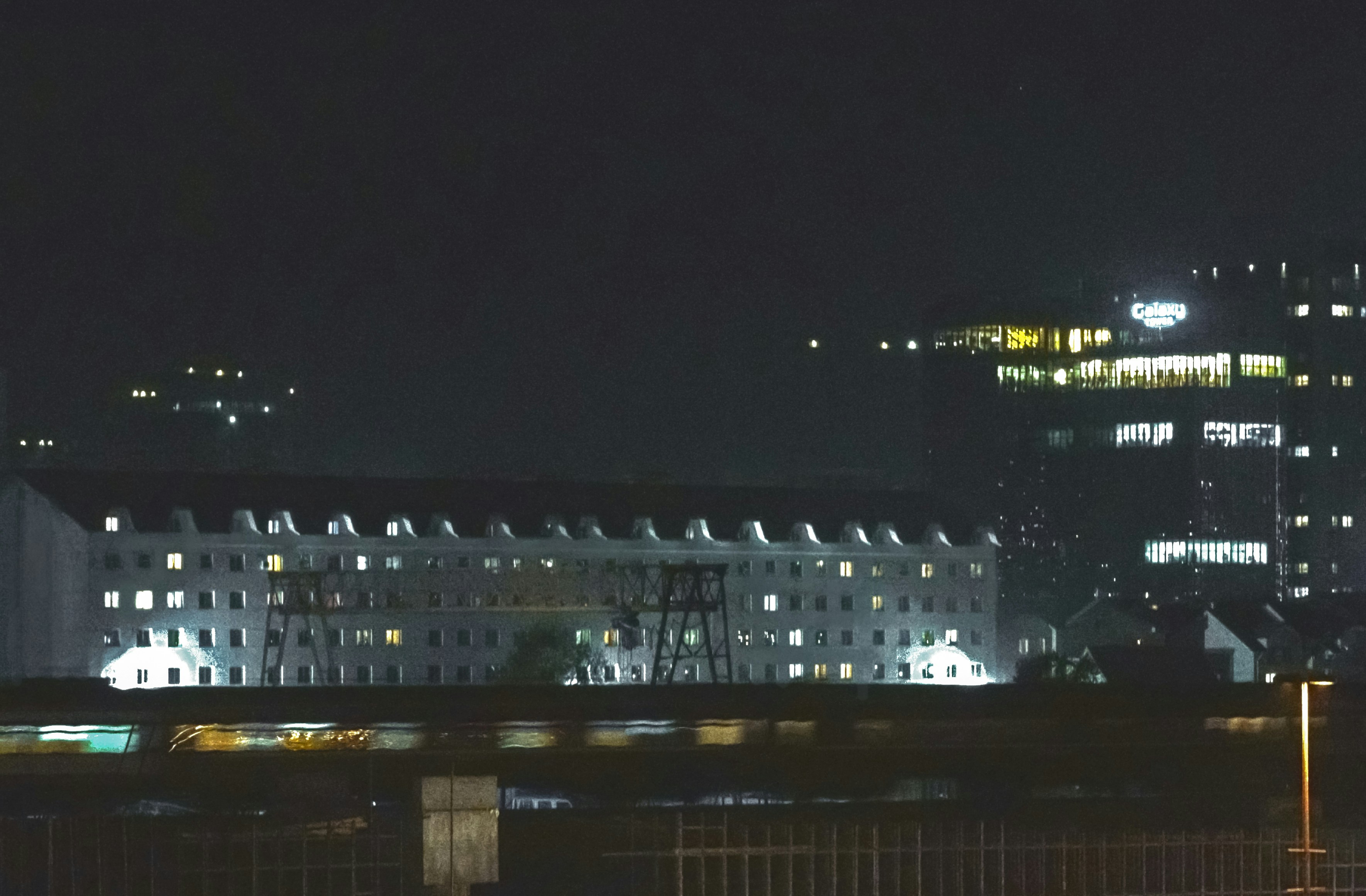 City skyline at night with illuminated buildings, dark atmospheric sky, urban architecture