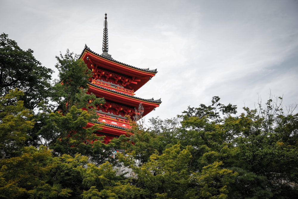 low-angle photo of red pagoda tower near trees