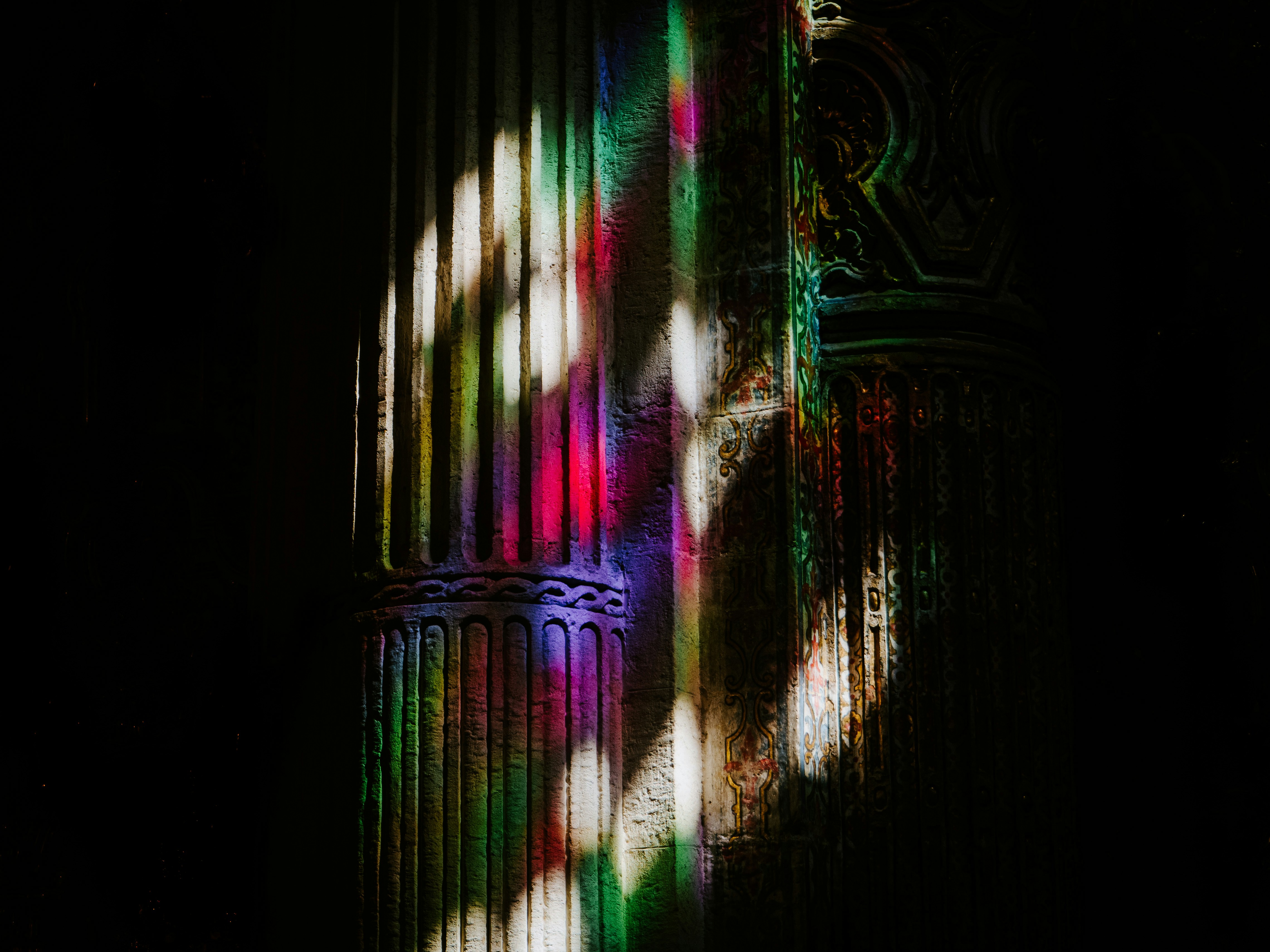 A cast of light through the stained glass of the dark Iglesia del Divino Salvador in Seville.