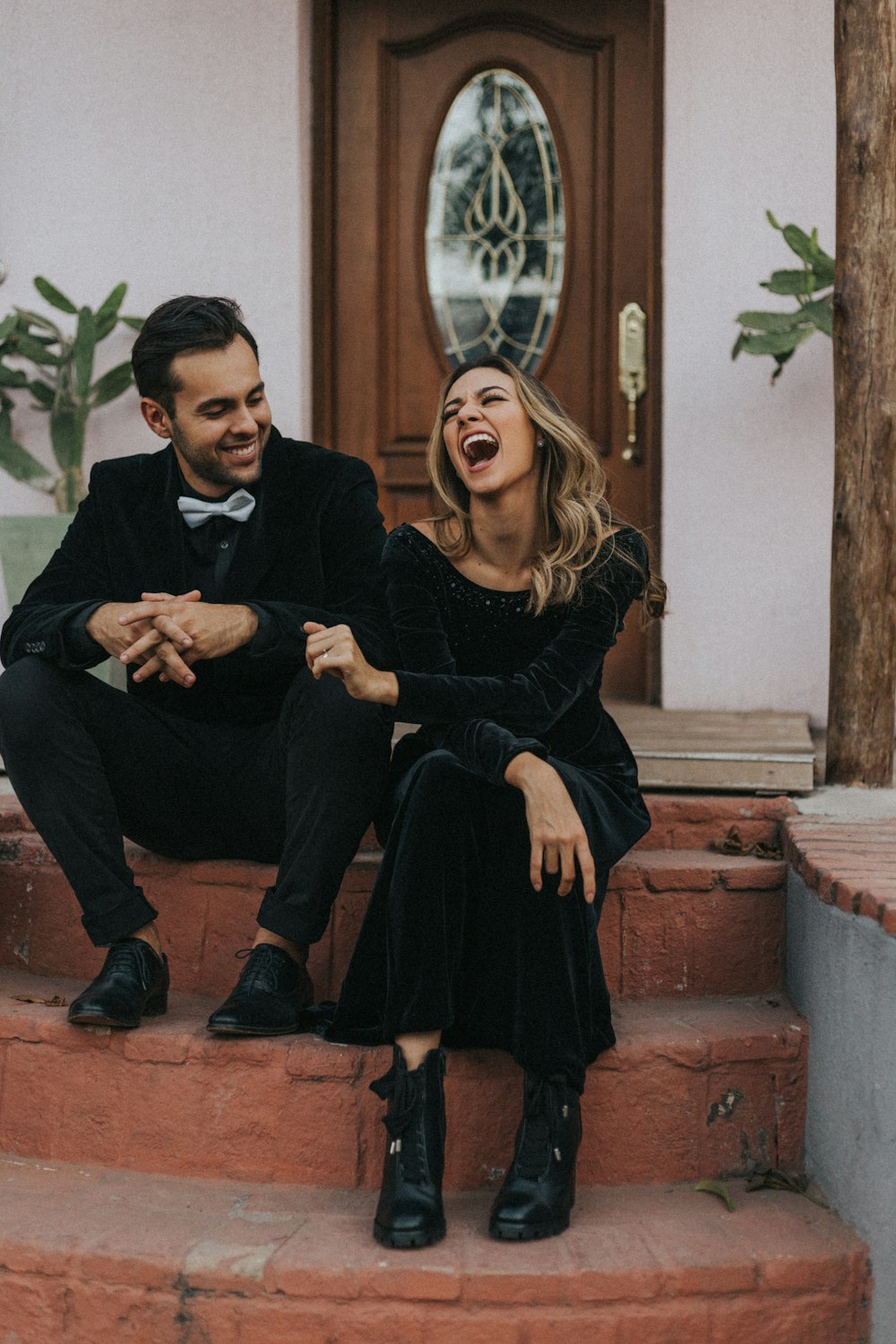 man and woman laughing outside house