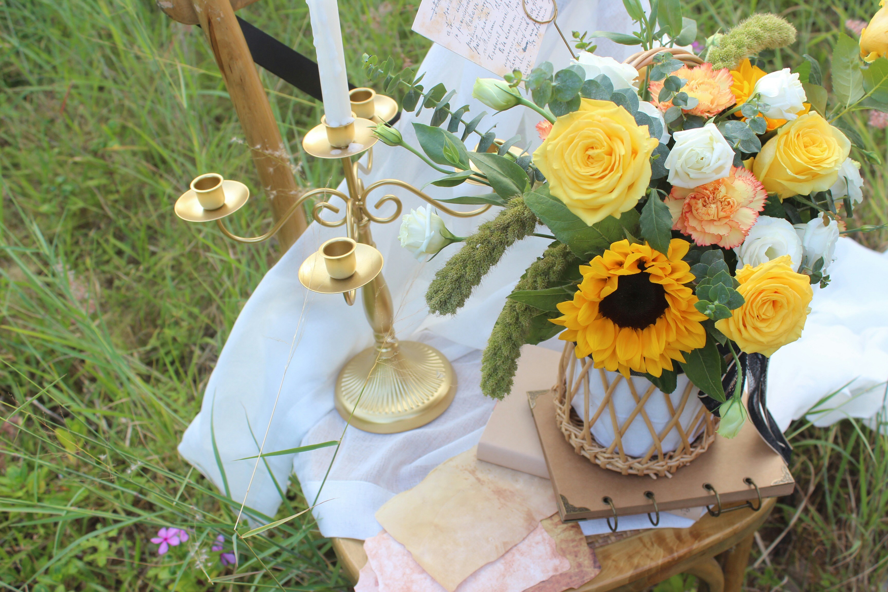 Yellow flowers and candle in grass