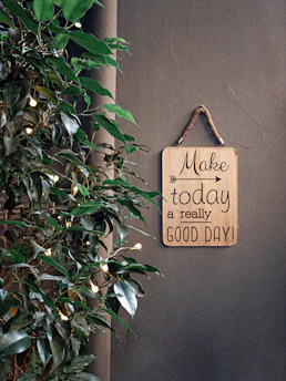brown make today a really good day signage beside green plant