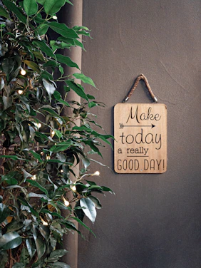brown make today a really good day signage beside green plant