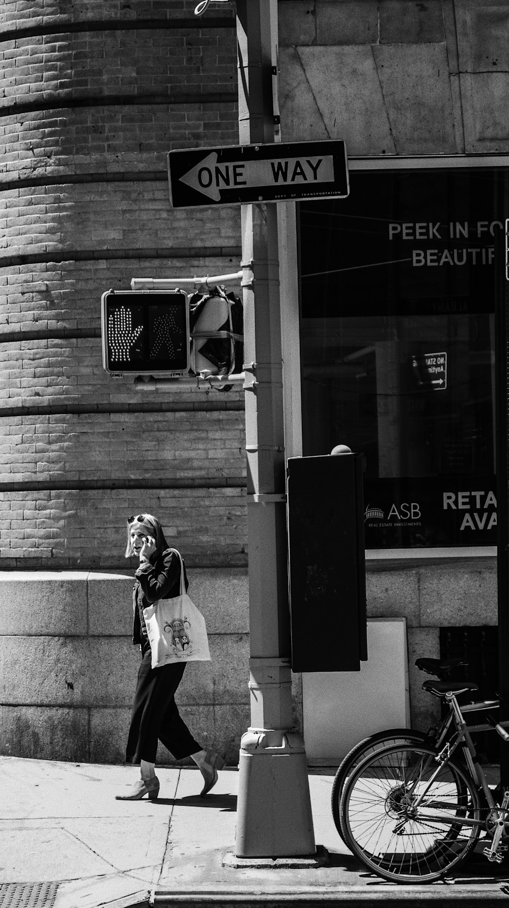 greyscale photography of woman walking beside building