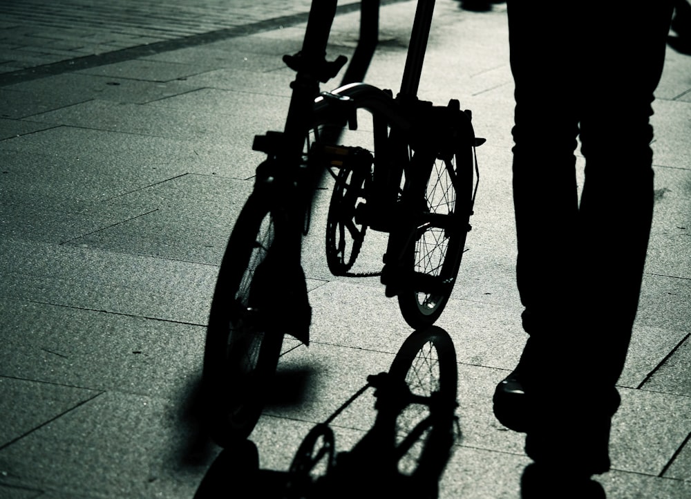 silhouette photo of person standing beside bicycle