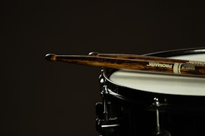 Close-up of drumsticks resting on a snare drum ready for a rhythm session.
