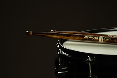 A close-up of drumsticks resting on a snare drum, subtly hinting at Shaan Frenzy's musical side.