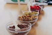 Artistic shot of a row of raspados with various vibrant syrups and toppings lined up on a clean counter.