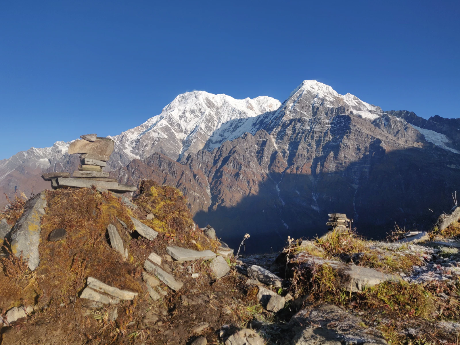 Stone cairns on a ridge with Annapurna South and the mountain wall rising behind, Nepal