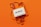 A vintage white cassette tape is placed on an orange background. The tape is partially unraveled, with the ribbon forming loose, swirling patterns around the cassette.