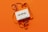 A vintage white cassette tape is placed on an orange background. The tape is partially unraveled, with the ribbon forming loose, swirling patterns around the cassette.