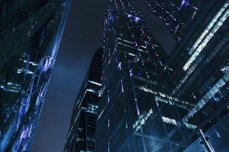A sleek, dark-toned city skyline at night with subtle silver highlights reflecting off glass surfaces.