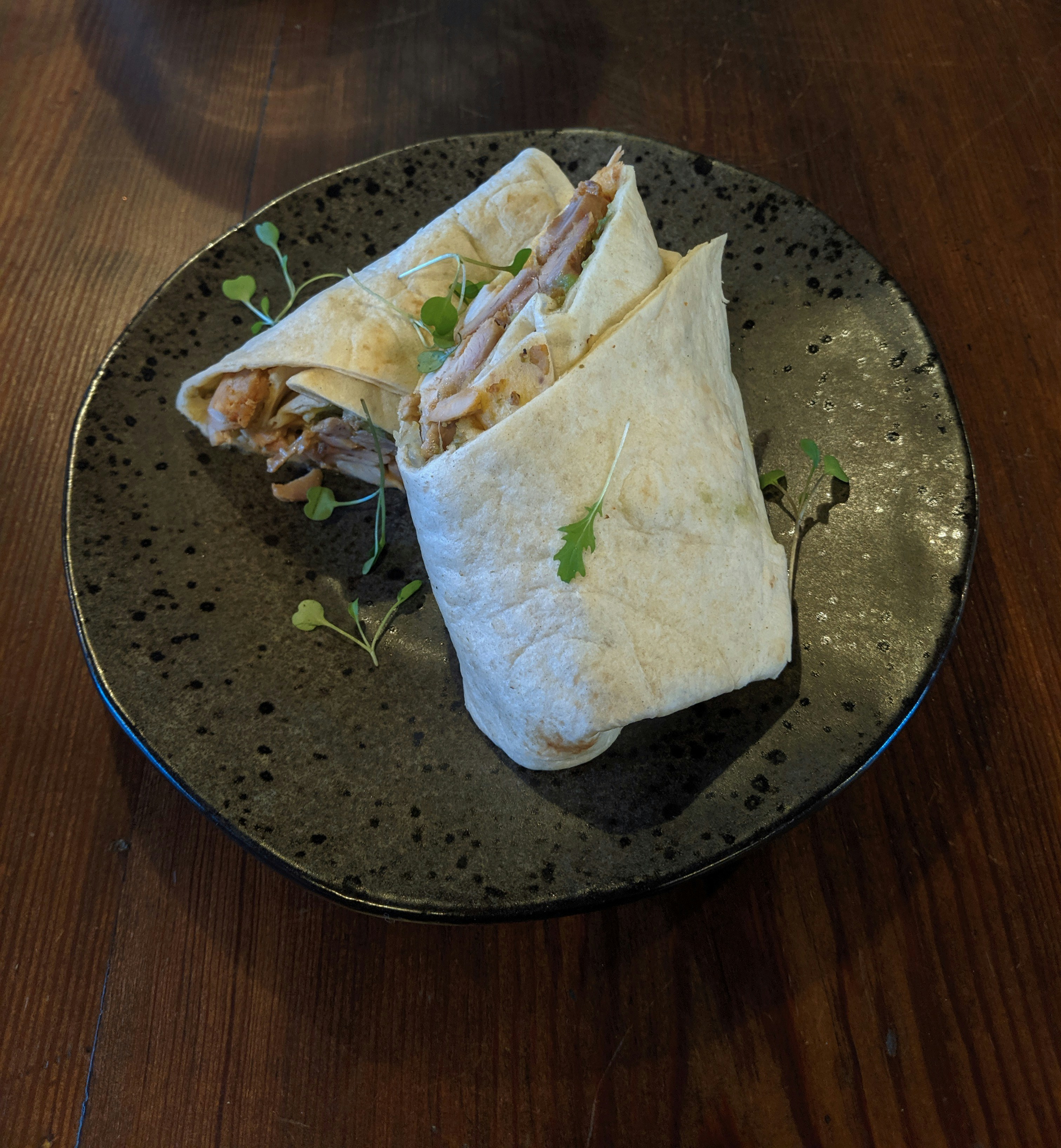 Grilled chicken wrap cut in half on a rustic plate