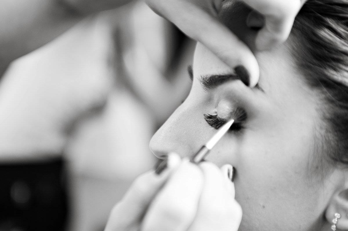 Makeup artist applying eye makeup to a seated client