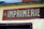 A weathered sign with the word 'IMPRIMERIE' prominently displayed in bold, serif letters on a red background. The number 46 is positioned to the left of the text. The sign is mounted on a light yellow wall, which appears to be part of an older building.