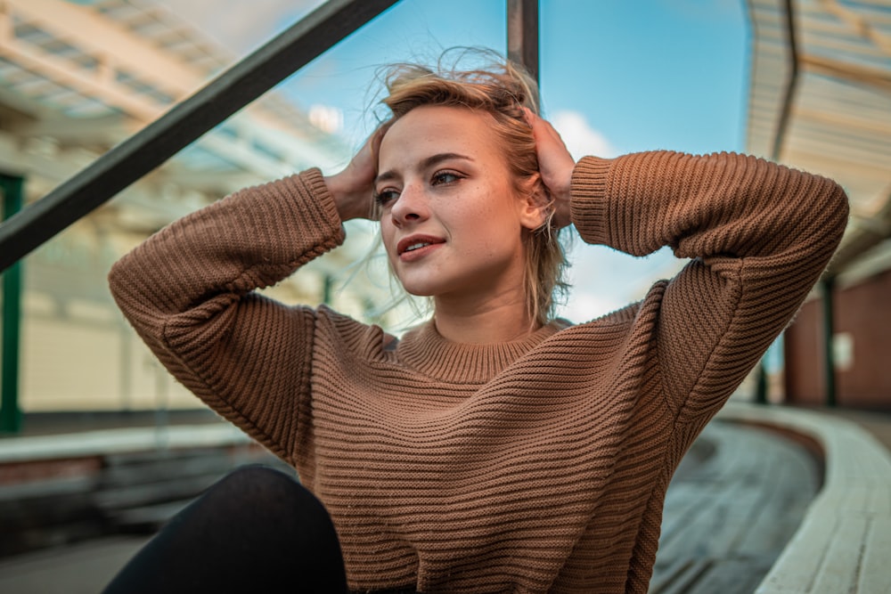 man wearing brown sweater both hands on side of head