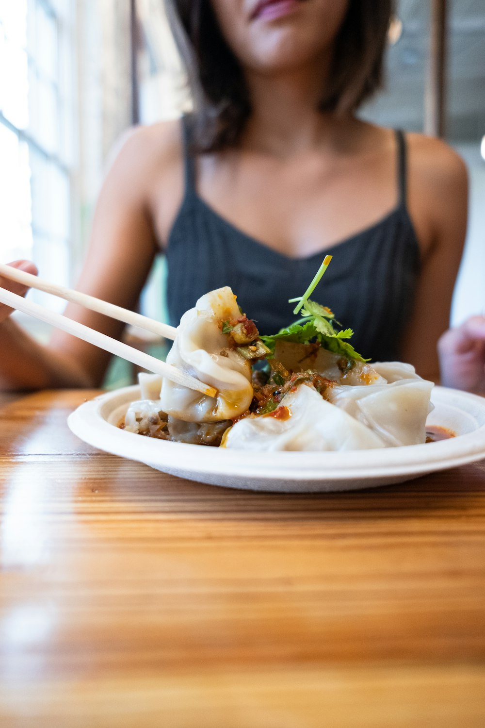 woman wearing black tank top holding chopstick