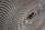 A close-up view of a corrugated cardboard material, showcasing its intricate honeycomb-like pattern. The image highlights the symmetrical, repetitive structure of the corrugated layers, creating a sense of depth and texture.