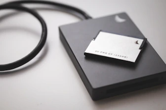 A sleek solid state drive being examined with specialized recovery tools on a bright workbench.