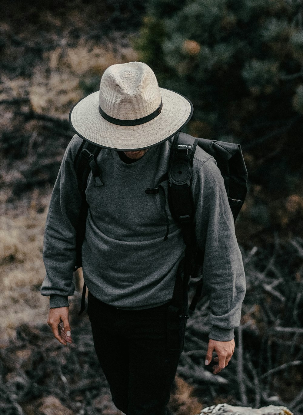 man walks and wears backpack, hat and sweatshirt