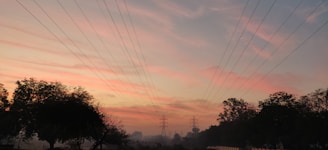 A team of electricians installing overhead power lines in a South Indian village at sunrise.