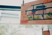 A detailed watercolor painting of a traditional Asian pagoda with green and red accents is clipped and displayed against a softly blurred background. The scene outside the window is reminiscent of the depicted architecture, suggesting a connection between the artwork and its surroundings.