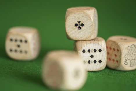 Hands rolling dice on a wooden table with a colorful game map in the background.
