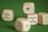 A close-up view of wooden dice with playing card suit symbols and numbers on their faces, resting on a green felt surface.
