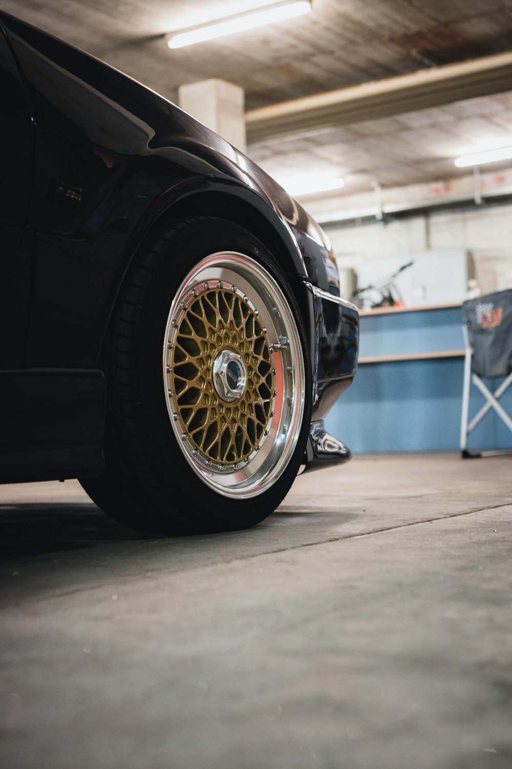 Une voiture noire avec des jantes dorées garée dans un garage