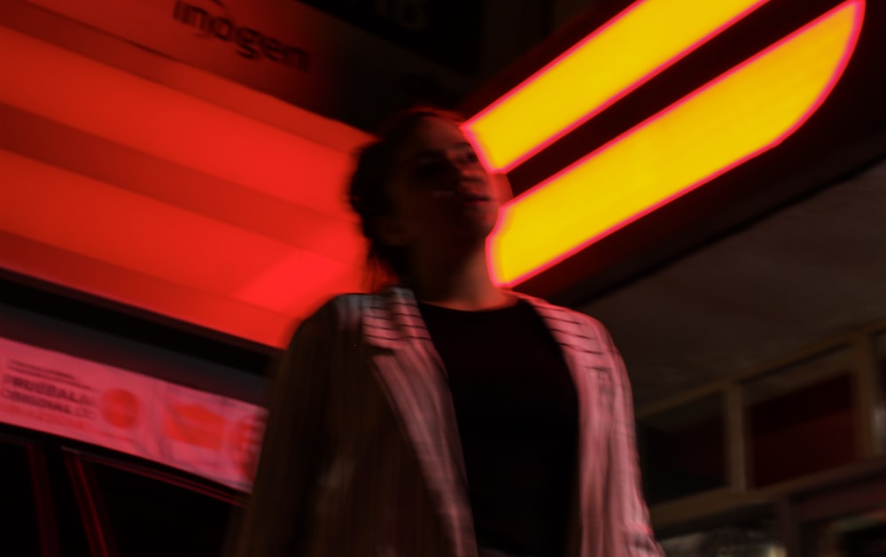 a woman standing in front of a neon sign