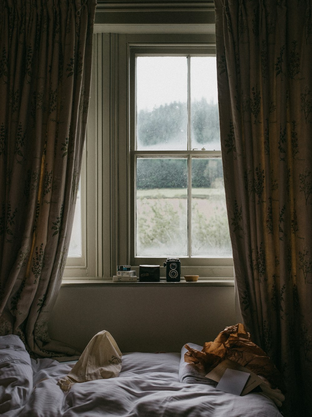 bed beside window with curtains during day