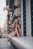 woman sitting near gray concrete wall