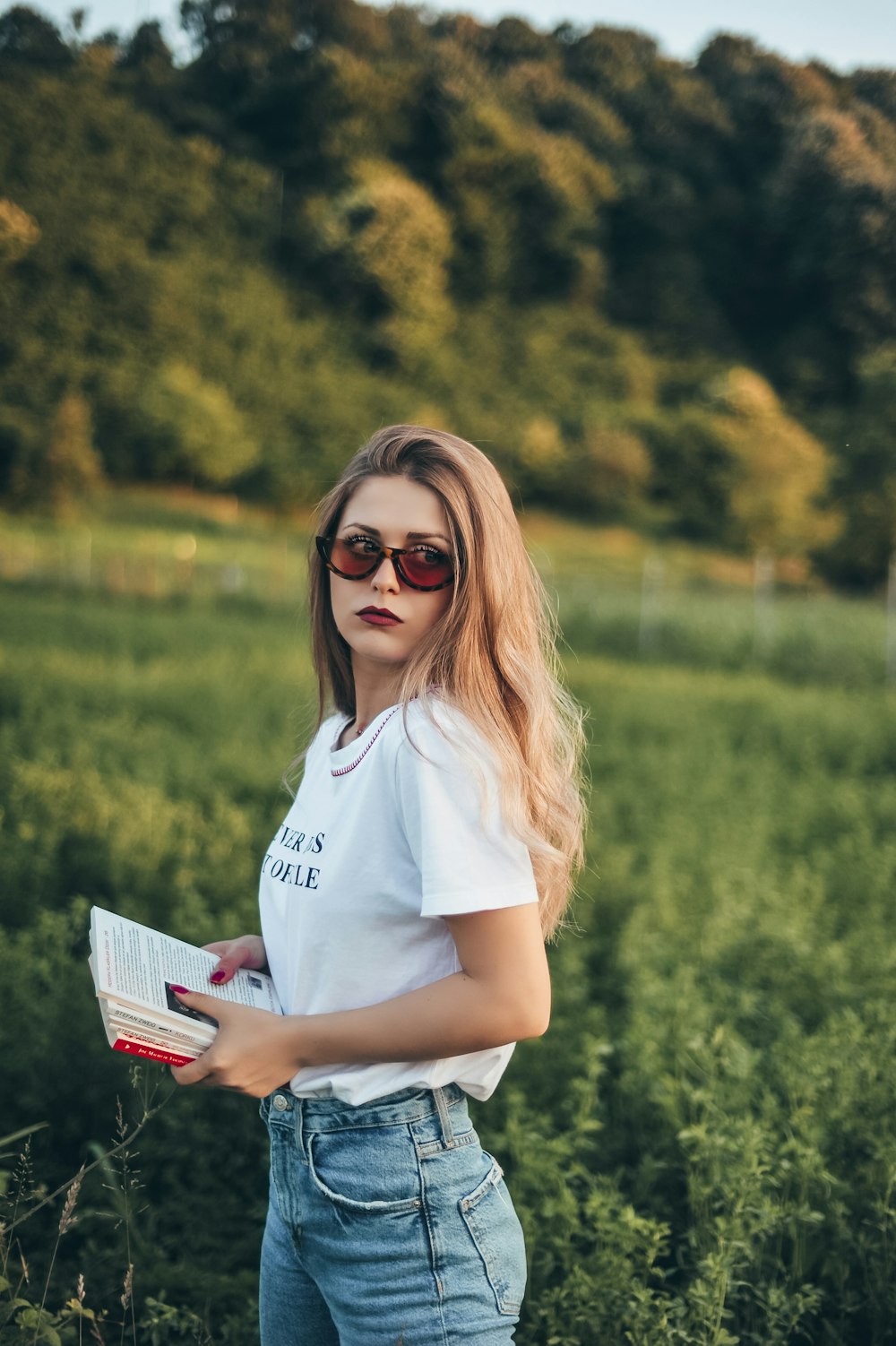 woman holding papers near grass field