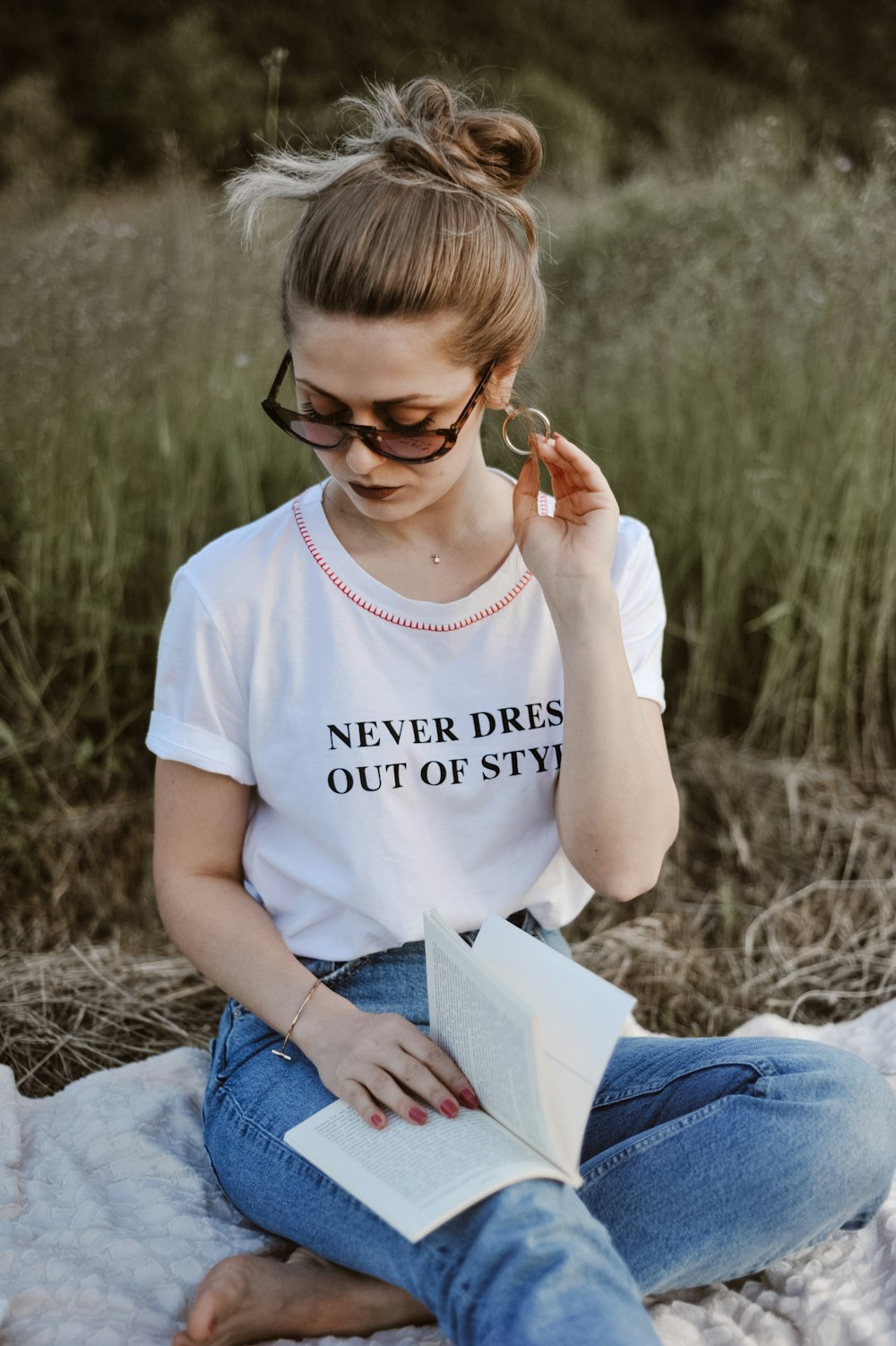 woman wearing white shirt and blue jeans holding white book