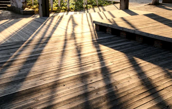 A craftsman fixing wooden deck boards with tools on a sunny day