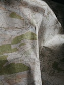 A detailed topographical map with green, blue, and brown areas indicating various terrain features such as forests, rivers, and elevations. The map is slightly crumpled, adding a textured appearance.